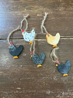 four chicken ornaments hanging from twine on wooden table