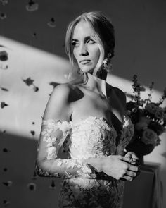 black and white photograph of a woman in a dress with flowers on the wall behind her