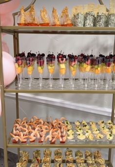 an assortment of desserts and snacks displayed on three tiered trays with wine glasses