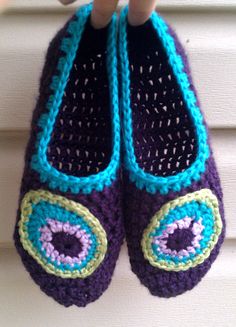 crocheted purple slippers with blue and green eyes hanging from a hook on a white door