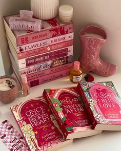 a stack of pink books sitting on top of a white table next to a vase