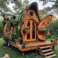 a house made out of wood and plants on the outside, with a butterfly shaped door