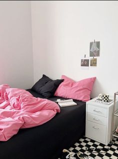 a black and white checkered floor in a bedroom with pink sheets on the bed