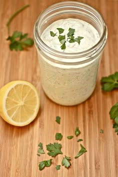 a jar filled with white sauce next to a sliced lemon