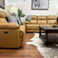 a living room with two couches and a coffee table in front of a cowhide rug