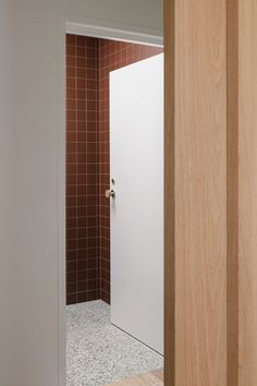 an open door leading to a bathroom with tiled walls and flooring on the other side