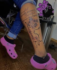 a woman's legs with pink clogs and flowers on her leg, while sitting