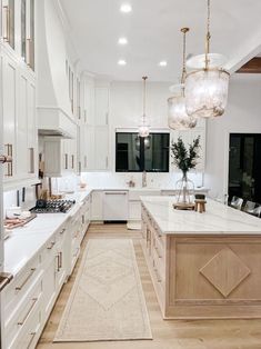 a large kitchen with white cabinets and an island in the middle is seen through a doorway