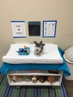 a small dog sitting on top of a bed next to a wall with pictures above it