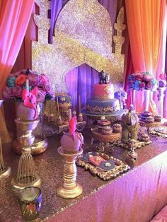 a table topped with lots of cakes and desserts on top of a purple table cloth