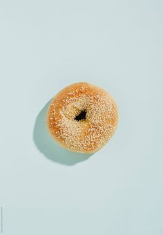 a donut with sesame sprinkles is shown on a light blue background