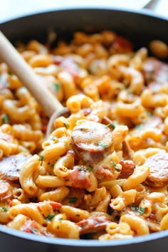 a bowl filled with pasta and meat on top of a wooden spoon in the middle