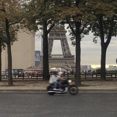 two people on a motorcycle passing by the eiffel tower in paris, france