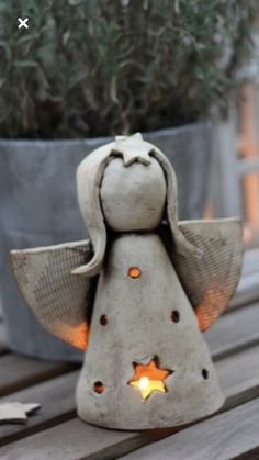 an angel statue sitting on top of a wooden table next to a potted plant