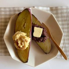 a white plate topped with an eggplant covered in butter next to a spoon