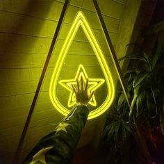 a person holding their hand up in front of a neon sign with a star on it