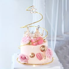 a three tiered cake decorated with pink roses and gold accents on a white stand