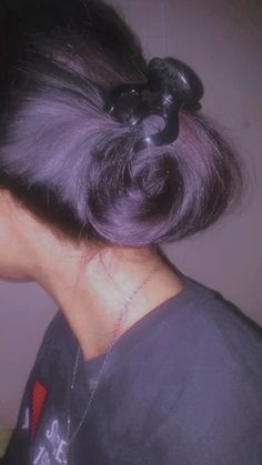 the back of a woman's head with purple hair and a black bow in it