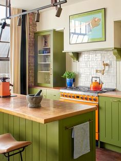 a kitchen with green cabinets and an island in front of a stove top oven next to a window