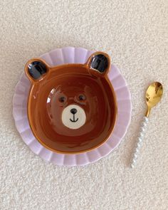 a plate with a bear face on it next to a spoon