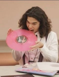 a man holding a pink frisbee in his right hand and making a face