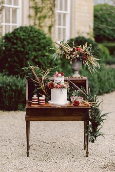 a table topped with a white cake covered in frosting and surrounded by greenery