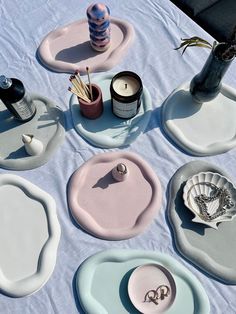 a table topped with plates and candles on top of a blue cloth