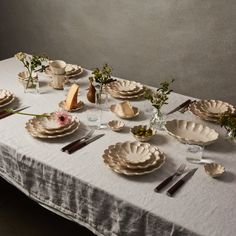 the table is set with plates, silverware and flower arrangements on top of it