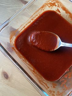 a spoon in a glass container filled with sauce