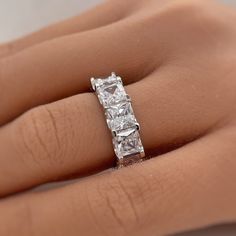 a woman's hand with a three stone ring on her left hand, showing the center diamond