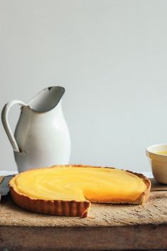 a piece of cheese is on a cutting board next to a knife and bowl with butter