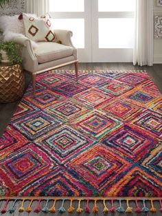 a multicolored area rug with a wooden bench in the corner and window behind it