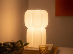 a white lamp sitting on top of a wooden table next to a potted plant