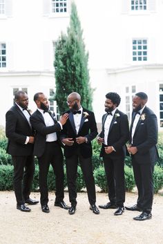 a group of men standing next to each other wearing tuxedos and bow ties