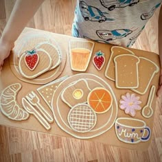 a child is holding a piece of paper with cut out food items on it in front of them