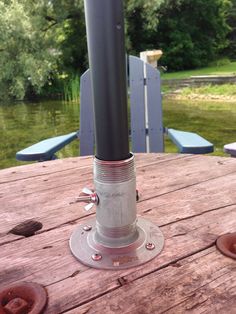 an outdoor table that has some kind of metal object on it's top and is next to the water