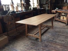 a wooden table sitting on top of a hard wood floor in a room filled with tools