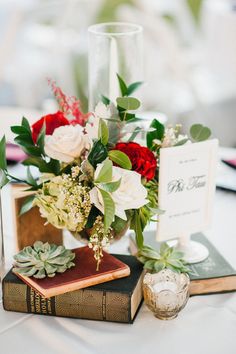 a table topped with books and flowers on top of a white table cloth covered table