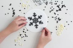 a person is making a snowflake out of bead sprinkles