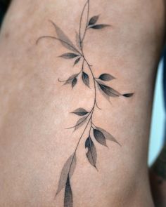 a woman's lower back tattoo with leaves on it