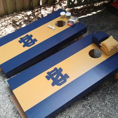 two blue and yellow cornhole game boards sitting on the ground