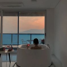 a woman sitting in a large bathtub next to a table with wine glasses on it