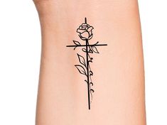 a cross and rose tattoo on the side of a woman's leg, with words written in cursive writing