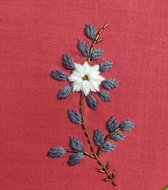 a close up of a flower on a pink cloth with green stems and white flowers