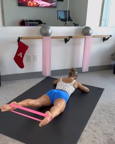 a woman laying on a mat with a pink band around her ankles and feet in the air