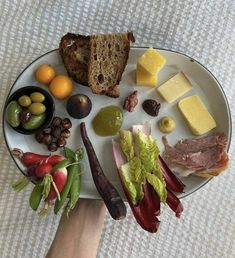 a white plate topped with lots of different types of food next to a person's hand