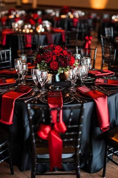 the table is set with black and red linens, silverware, and roses