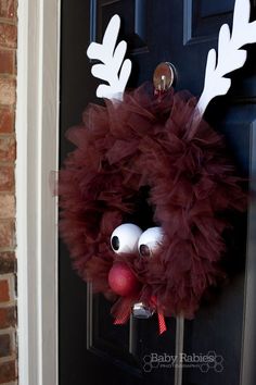 a red wreath with white feathers and an antlers on it is hanging from the front door