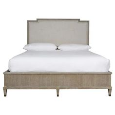 an upholstered bed with white sheets and pillows