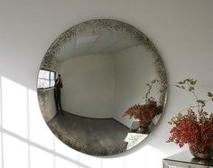 a person standing in front of a mirror with flowers on the wall next to it